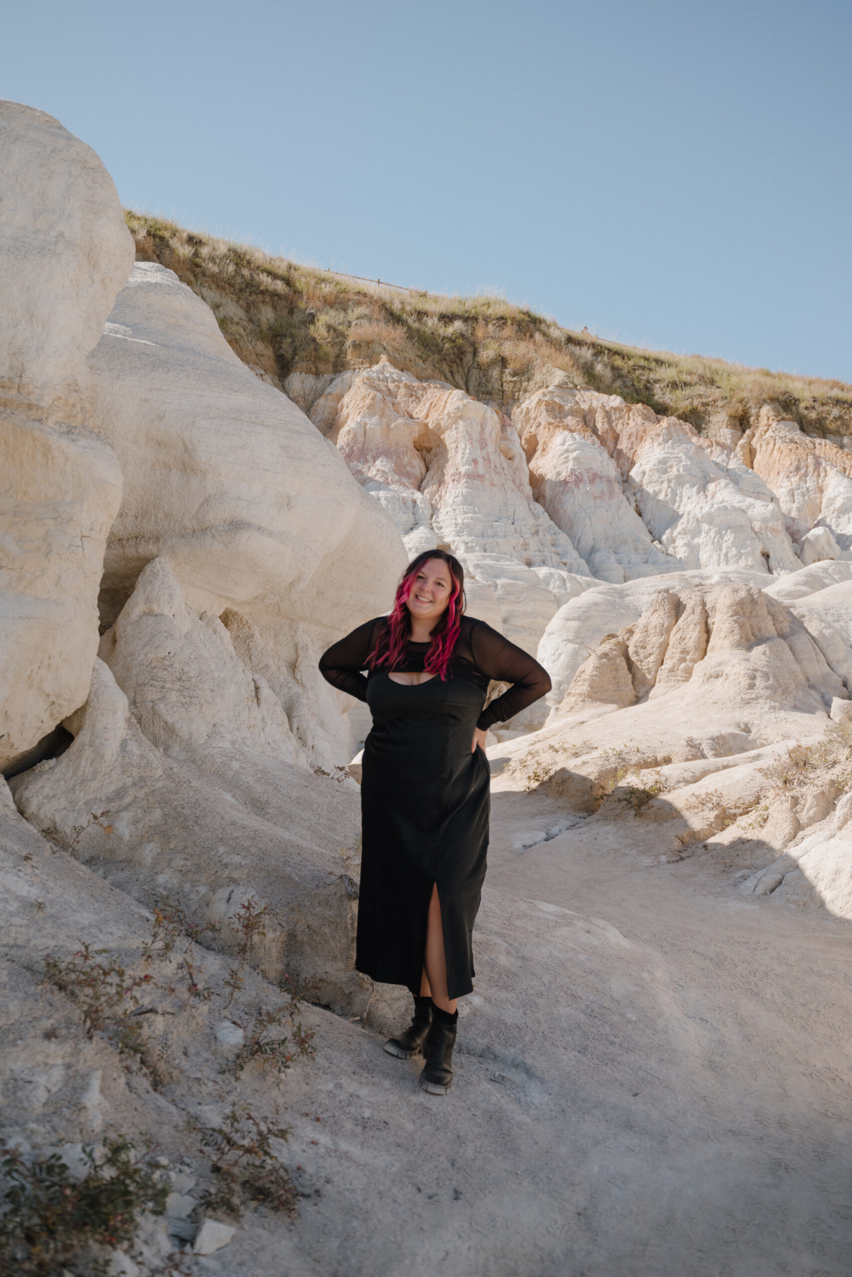 Girl in all black dress and black boots with hot pink hair in sandstone rock park in colorado